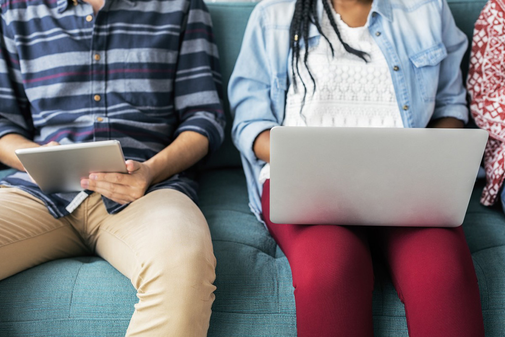 people seated side-by-side using laptops and tablets